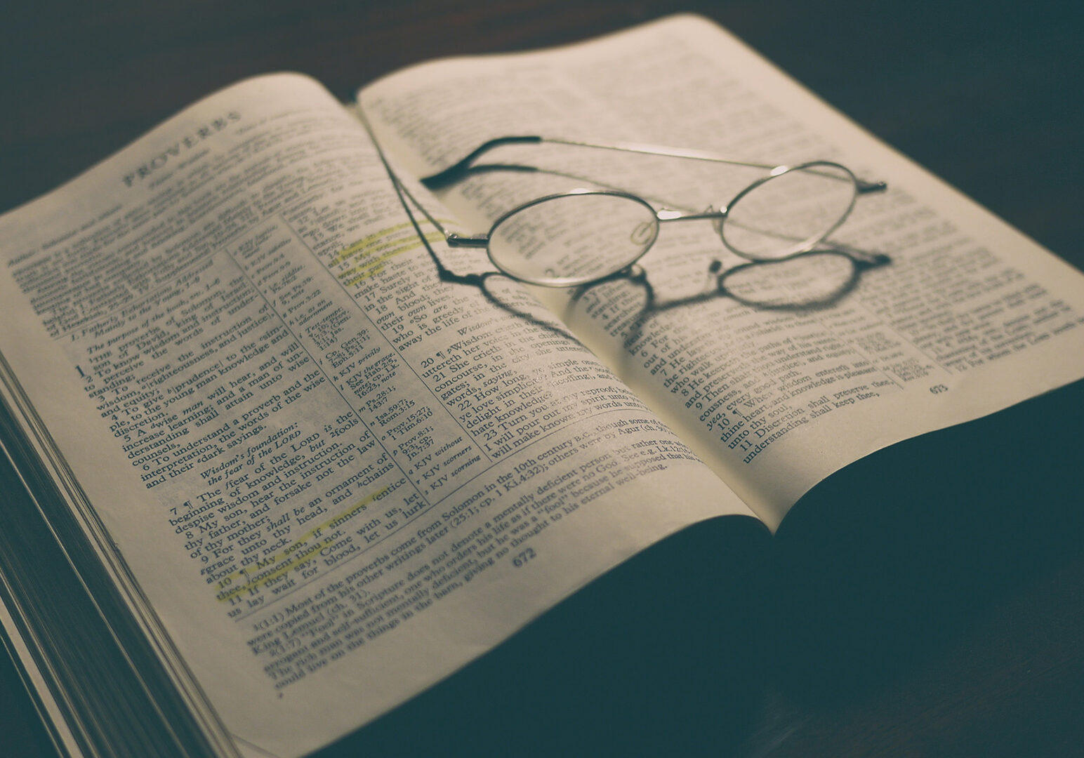 gray-framed-eyeglasses-on-open-book-Proverbs