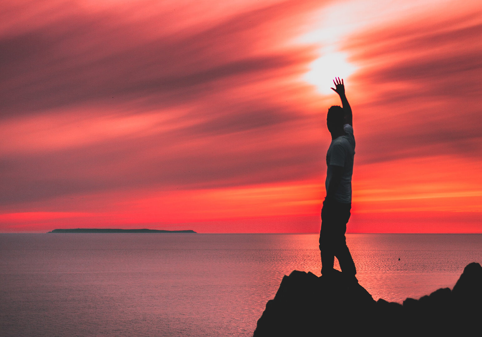 man-standing-on-rock-formation-near-body-of-water