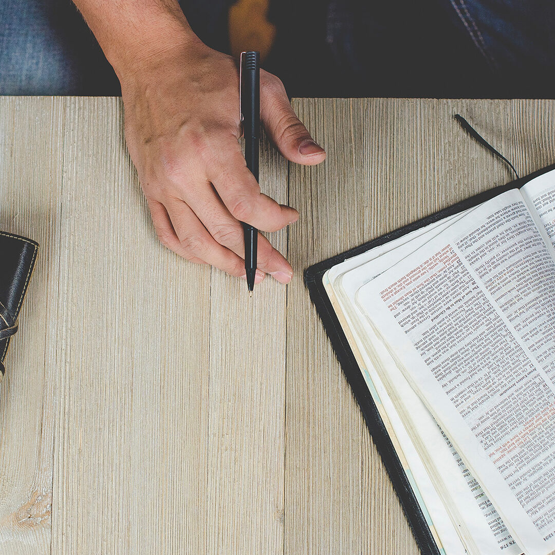 person-holding-bible-with-pen